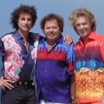De drie leden van Die Flippers in kleurrijke shirts voor de zee