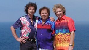 De drie leden van Die Flippers in kleurrijke shirts voor de zee