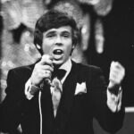 John Lamers in smoking zingt achter de microfoon op het Nationaal Songfestival van 1969