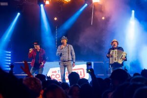 The Dutch Boys op het podium van C'est la Vie in Emmen: twee zangers met hoed en een accordeonist